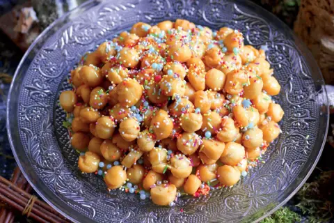 Struffoli ricetta della nonna: palline dorate fritte, ricoperte di miele e confettini colorati, su un piatto decorato.