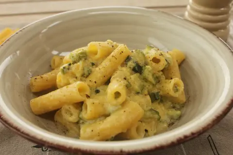 Piatto di rigatoni cremosi con carbonara di zucchine, guarniti con pepe nero macinato fresco.