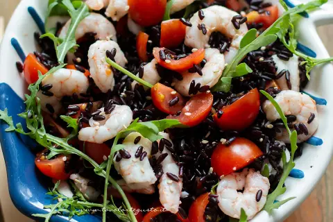 Insalata colorata con riso venere, gamberetti succosi, pomodorini freschi e rucola croccante. Un piatto leggero e gustoso.