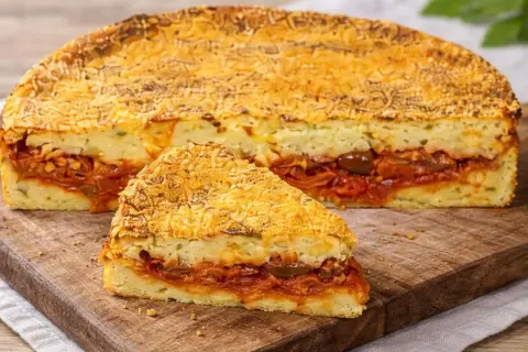 Una fetta di pitta di patate, con strati di ripieno saporito e crosta dorata, pronta per essere gustata.
