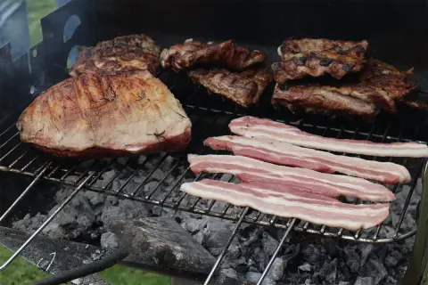 Grigliata di carne con costine, arrosto e pancetta che sfrigolano sulla brace.
