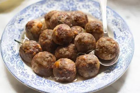 Polpette dorate e succulente in friggitrice ad aria, servite su un piatto di ceramica blu e bianco.