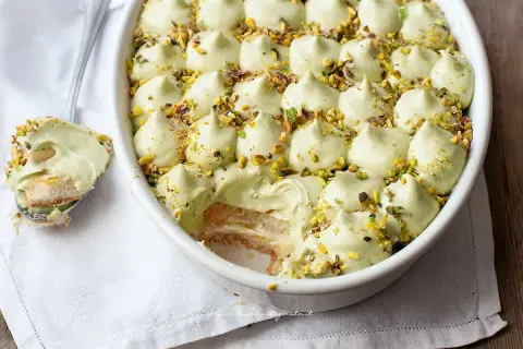 Delizioso tiramisù senza caffè, con crema al pistacchio e biscotti savoiardi, guarnito con granella di pistacchi.