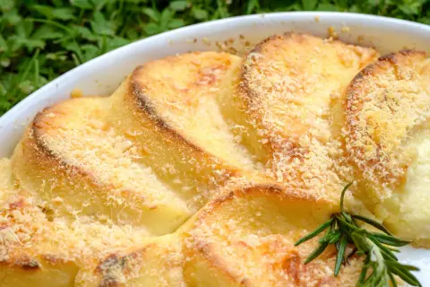 Gnocchi alla romana dorati e gratinati, serviti in una teglia bianca con un rametto di rosmarino.