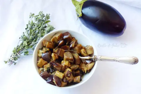 Melanzane in padella, un contorno saporito, con un mazzetto di erbe aromatiche e una melanzana intera.