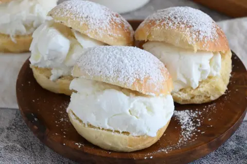 Tre soffici brioche con gelato alla vaniglia, spolverate di zucchero a velo, pronte per essere gustate.