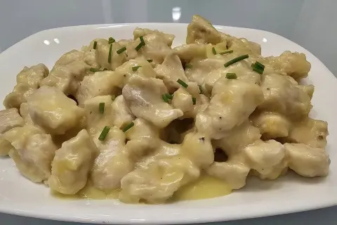 Straccetti di pollo cremosi, un piatto invitante con bocconcini di pollo in una salsa vellutata, guarniti con erba cipollina fresca.
