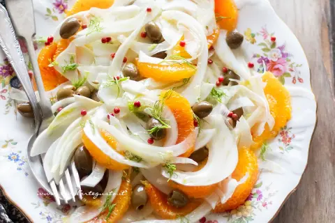Deliziosa insalata finocchi e arance, con olive verdi e pepe rosa, guarnita con finocchietto fresco. Un piatto fresco e colorato.