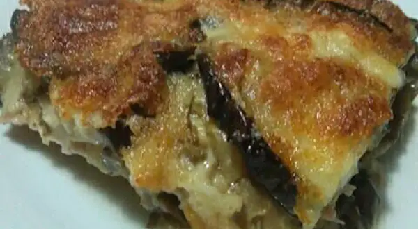 Una fetta di parmigiana di melanzane bianca, dorata e filante, con strati di melanzane e formaggio fuso.