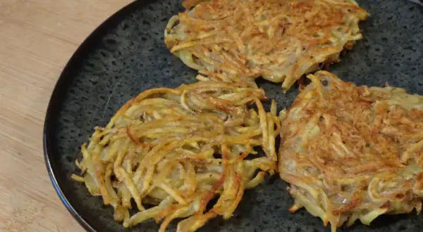 Tre croccanti rosti di patate in padella, dorati e pronti per essere gustati.