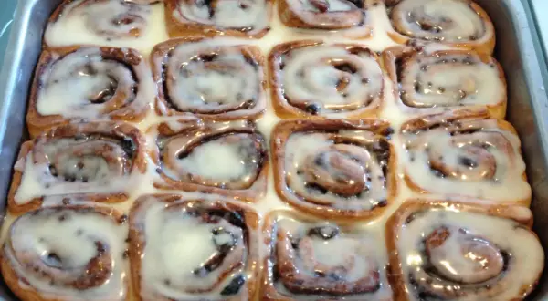 Rotolini alla cannella appena sfornati, ricoperti di glassa bianca e lucida, pronti per essere gustati.