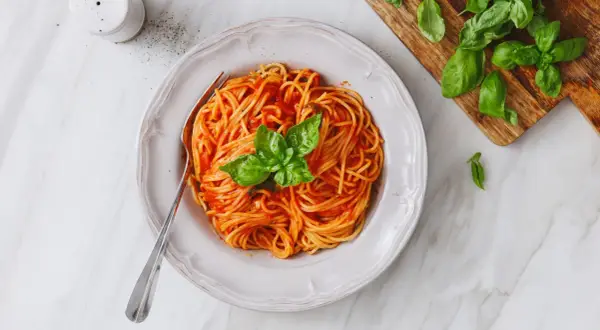 Un piatto invitante di pasta al pomodoro, condita con basilico fresco, pronta per essere gustata.
