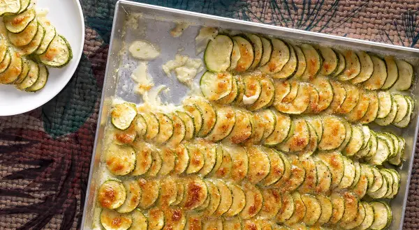 Fette di zucchine gratinate in teglia, un contorno di verdure dorato e invitante, pronto per essere gustato.