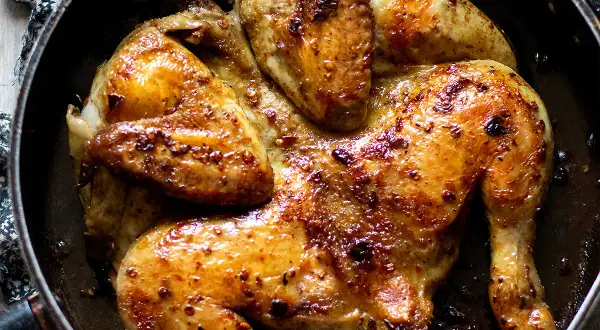 Pollo alla diavola succulento e dorato, cotto in padella con spezie piccanti.
