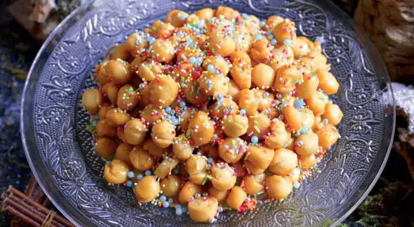 Struffoli ricetta della nonna: palline dorate fritte, ricoperte di miele e confettini colorati, su un piatto decorato.