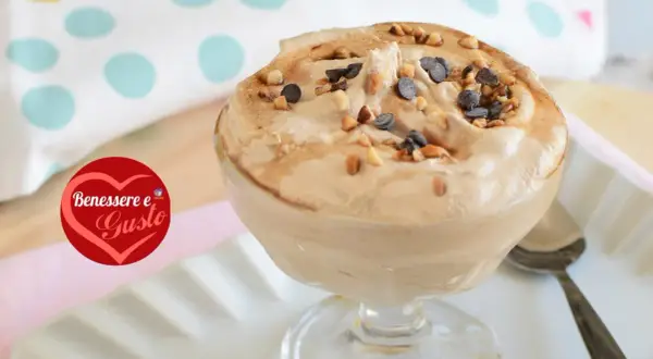 Deliziosa mousse al caffè, guarnita con nocciole tostate e gocce di cioccolato, servita in una coppa di vetro.