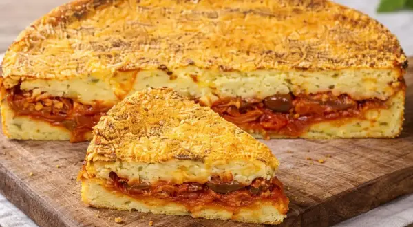 Una fetta di pitta di patate, con strati di ripieno saporito e crosta dorata, pronta per essere gustata.