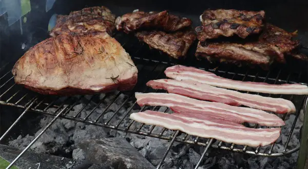 Grigliata di carne con costine, arrosto e pancetta che sfrigolano sulla brace.