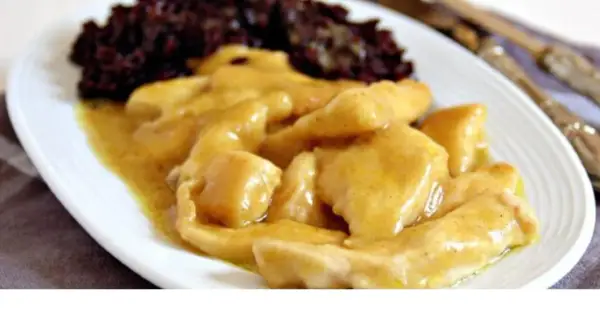 Straccetti di pollo al curry cremosi, serviti con riso nero. Un piatto saporito e invitante.