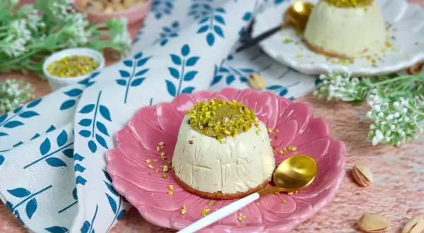 Delizioso semifreddo al pistacchio, guarnito con granella e crema di pistacchi, servito su un piatto rosa.