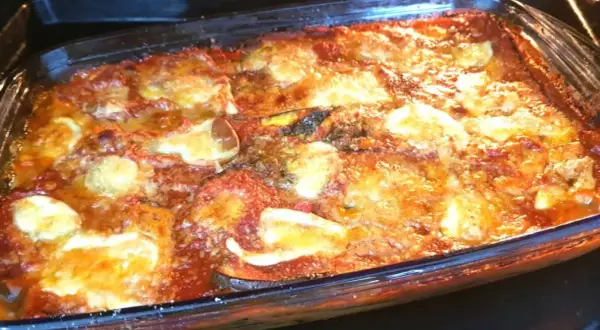Parmigiana di melanzane non fritte appena sfornata, dorata e filante, pronta per essere gustata.