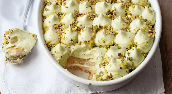 Delizioso tiramisù senza caffè, con crema al pistacchio e biscotti savoiardi, guarnito con granella di pistacchi.