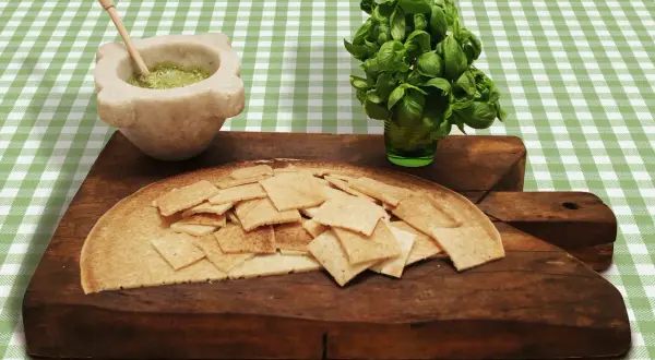 Testaroli al pesto pronti da gustare, con basilico fresco e mortaio.