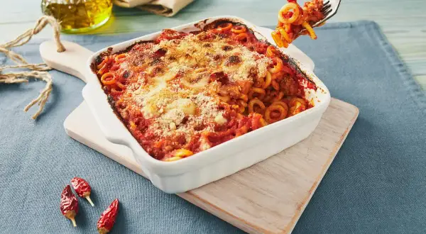 Piatto fumante di pasta alla siciliana, con sugo rosso e formaggio gratinato. Una forchettata pronta per essere gustata.