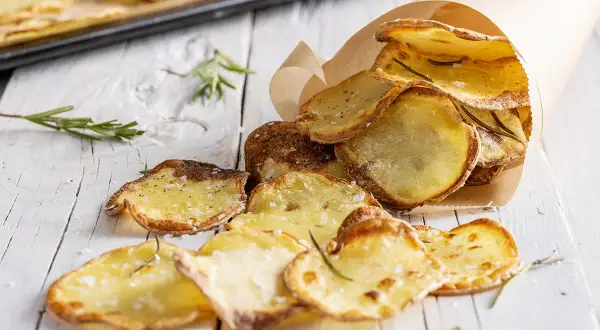 Croccanti chips di patate fatte in casa, condite con sale e rosmarino, servite in un cono di carta.
