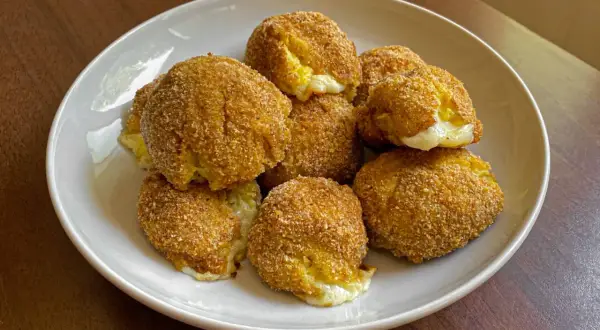 Piatto di polpette di patate dorate e croccanti, con un cuore filante di formaggio.
