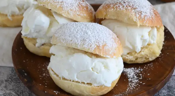 Tre soffici brioche con gelato alla vaniglia, spolverate di zucchero a velo, pronte per essere gustate.