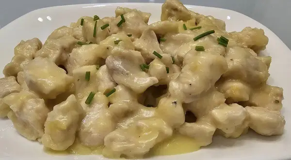 Straccetti di pollo cremosi, un piatto invitante con bocconcini di pollo in una salsa vellutata, guarniti con erba cipollina fresca.