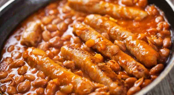 Salsiccia e fagioli in umido, un piatto confortante e saporito, servito in una padella scura.