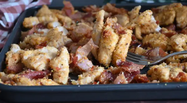 Straccetti di pollo al forno croccanti e saporiti, con fette di pancetta croccante, serviti in una teglia.