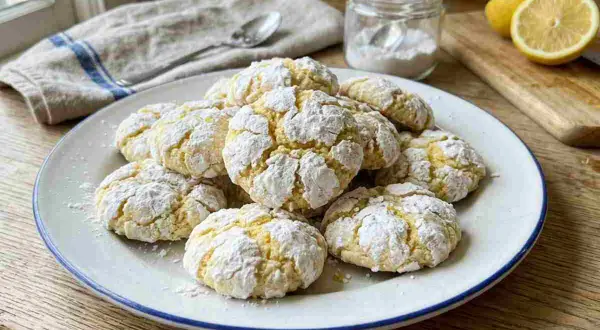 Piatto di biscotti al limone morbidi, spolverati di zucchero a velo, pronti per essere gustati.