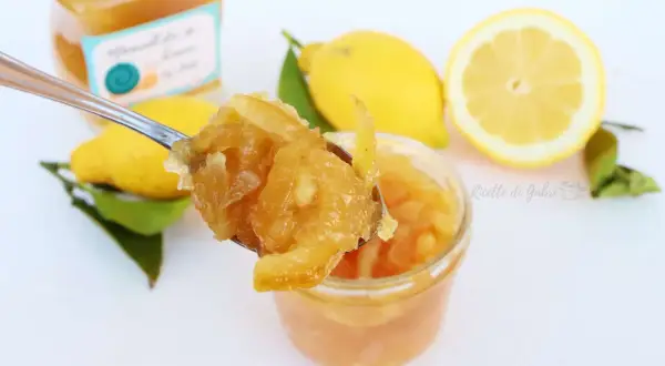 Marmellata di limone ricetta facile: un cucchiaio pieno di delizia, limoni freschi e un vasetto pronto da gustare.