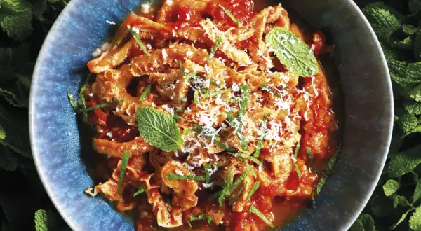 Trippa alla romana in un piatto blu, guarnita con menta e parmigiano. Un classico della cucina romana.