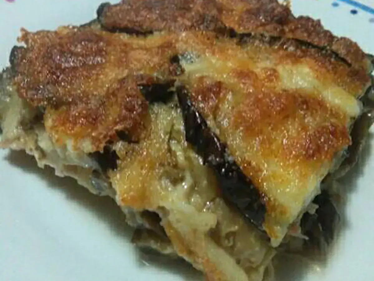 Una fetta di parmigiana di melanzane bianca, dorata e filante, con strati di melanzane e formaggio fuso.
