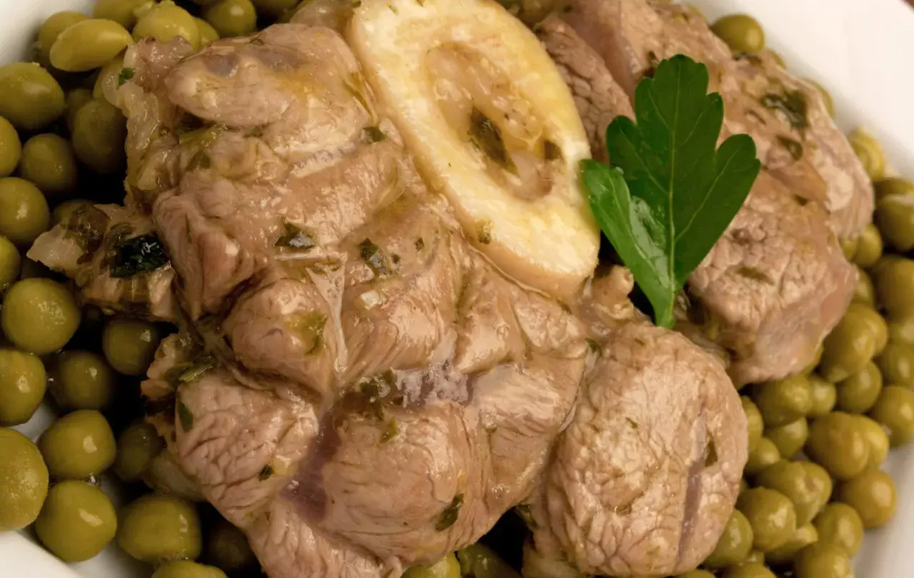 Ossobuco con piselli, un piatto succulento con carne tenera e piselli verdi brillanti, guarnito con una foglia di prezzemolo.