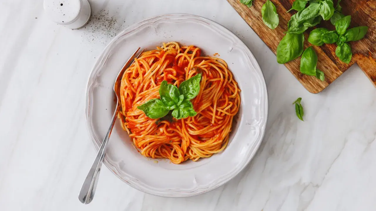 Un piatto invitante di pasta al pomodoro, condita con basilico fresco, pronta per essere gustata.