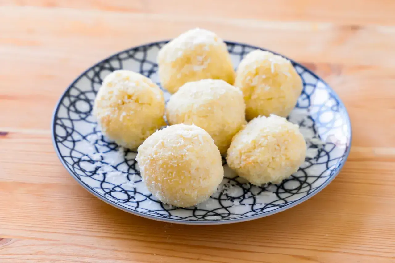 Piatto con dolcetti al cocco, soffici e bianchi, su un fondo di legno.