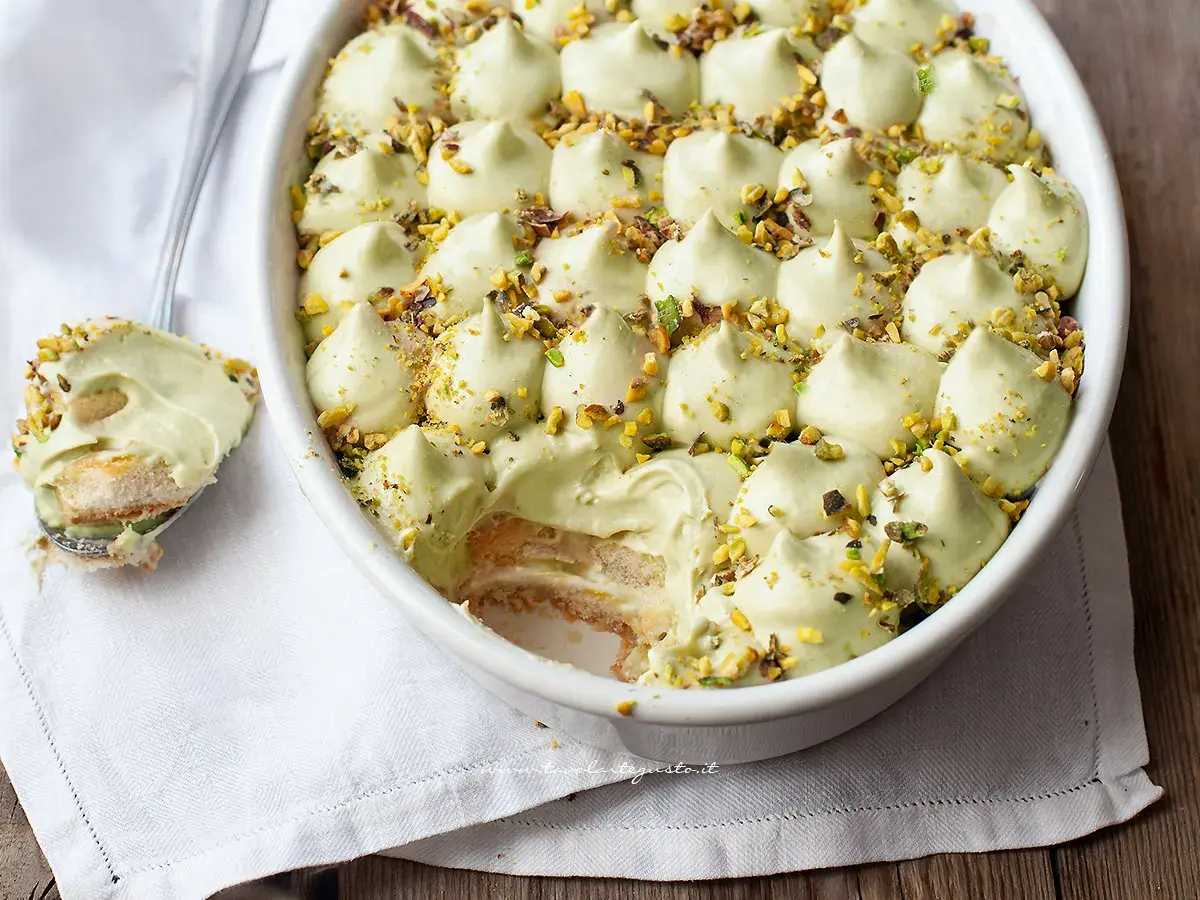 Delizioso tiramisù senza caffè, con crema al pistacchio e biscotti savoiardi, guarnito con granella di pistacchi.