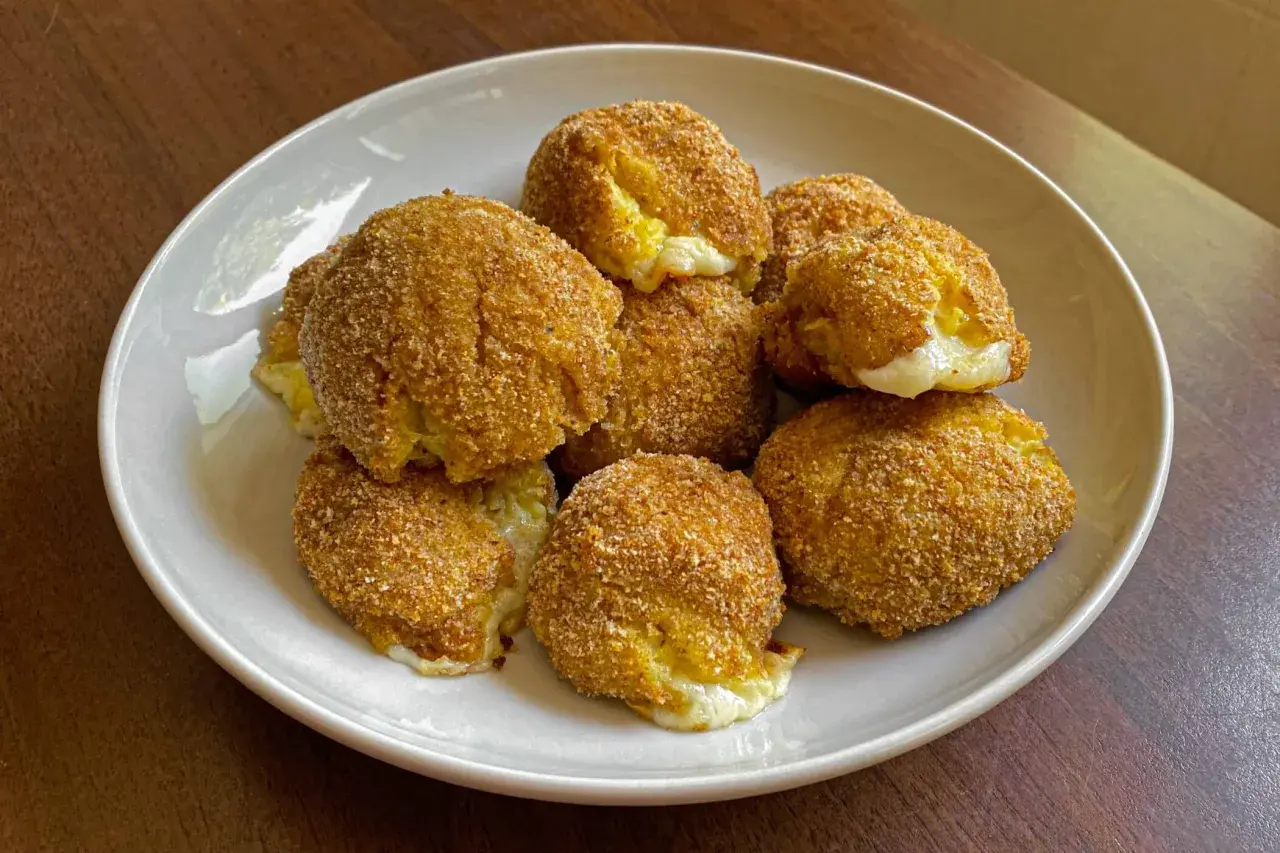 Piatto di polpette di patate dorate e croccanti, con un cuore filante di formaggio.