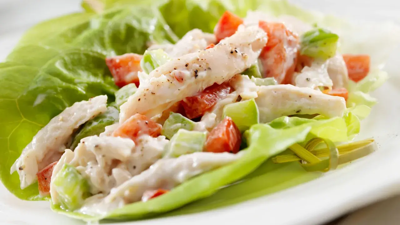 Insalata di pollo con maionese, pomodoro e sedano, servita su foglie di lattuga croccante. Una ricetta fresca e gustosa.