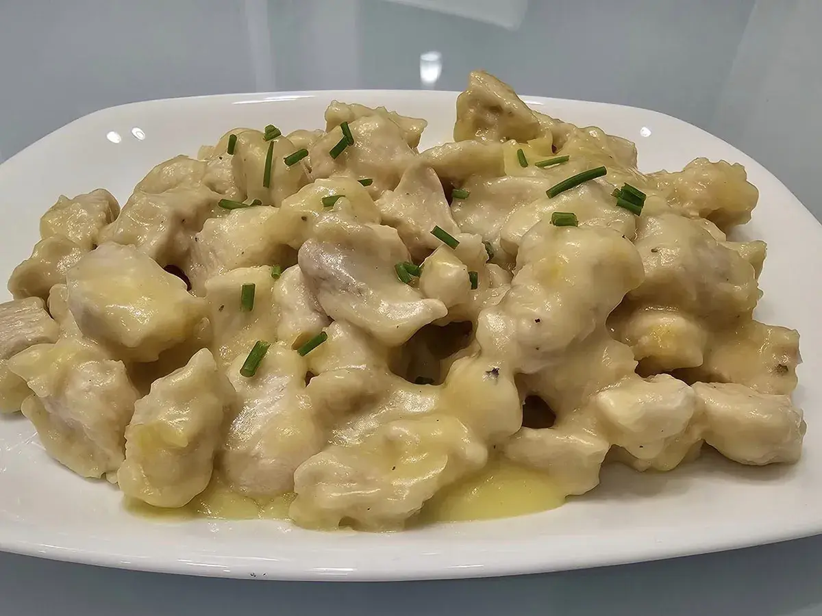 Straccetti di pollo cremosi, un piatto invitante con bocconcini di pollo in una salsa vellutata, guarniti con erba cipollina fresca.
