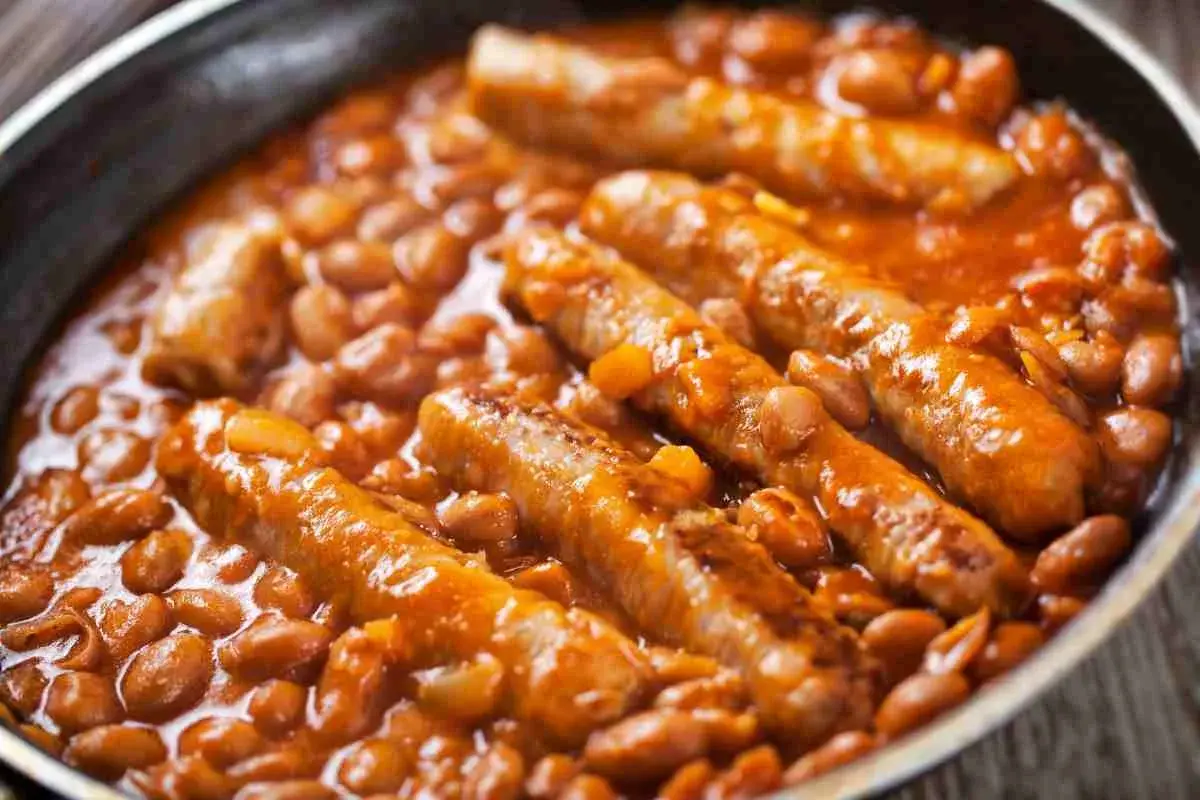 Salsiccia e fagioli in umido, un piatto confortante e saporito, servito in una padella scura.