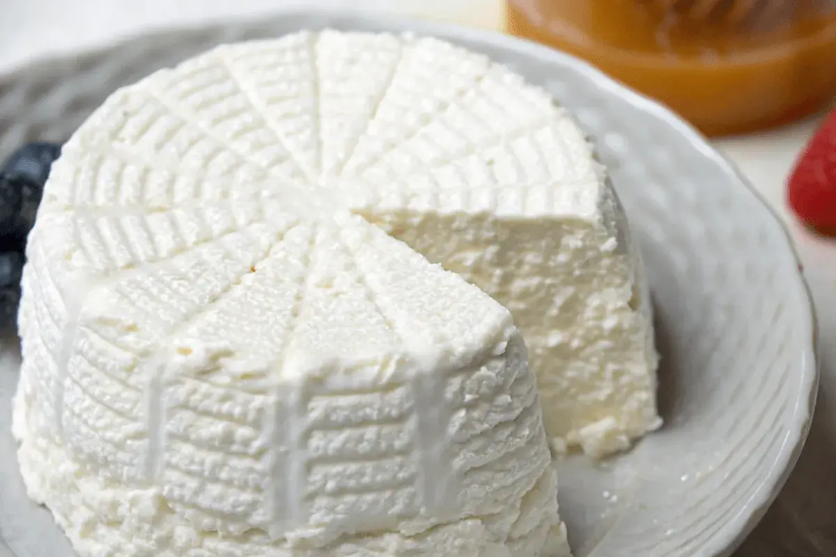 Ricotta fatta in casa, fresca e cremosa, servita su un piatto con mirtilli e fragole.