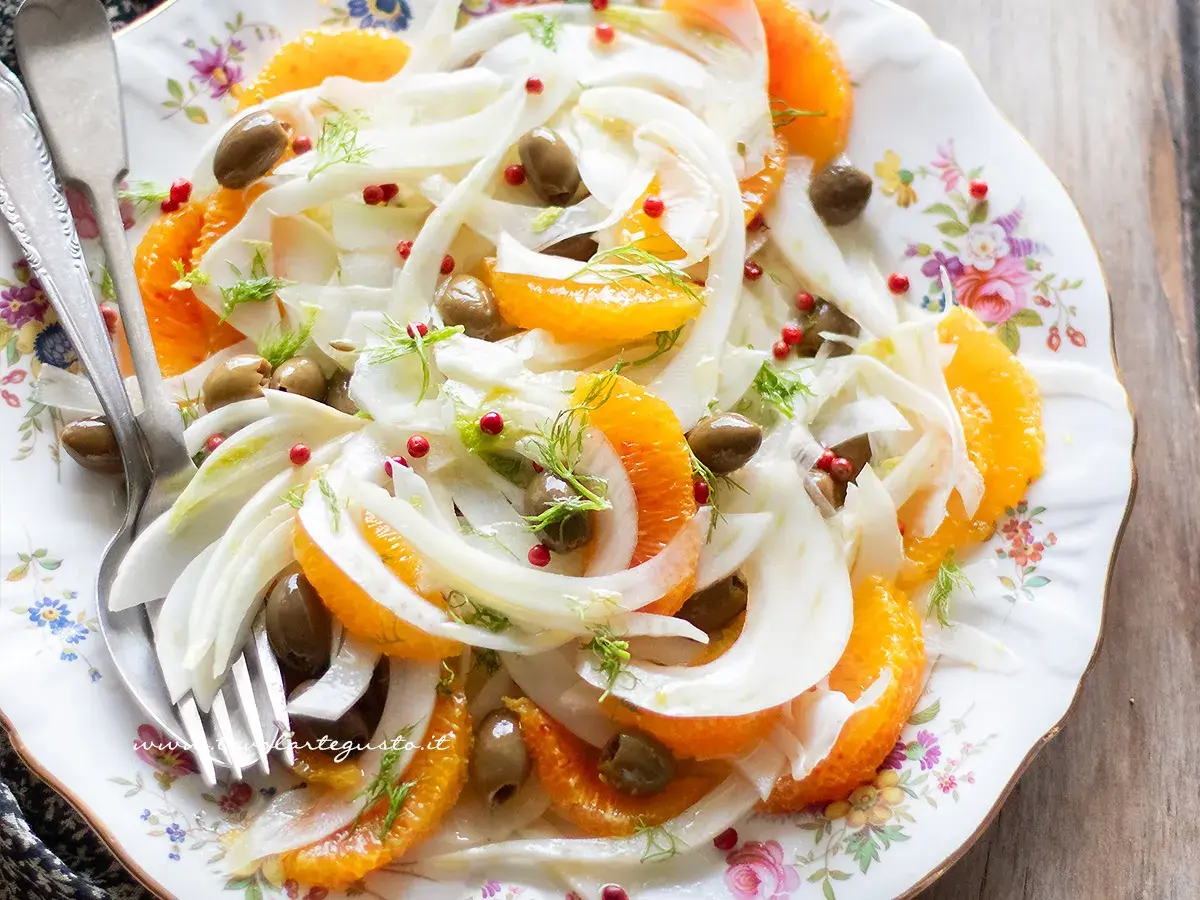Deliziosa insalata finocchi e arance, con olive verdi e pepe rosa, guarnita con finocchietto fresco. Un piatto fresco e colorato.
