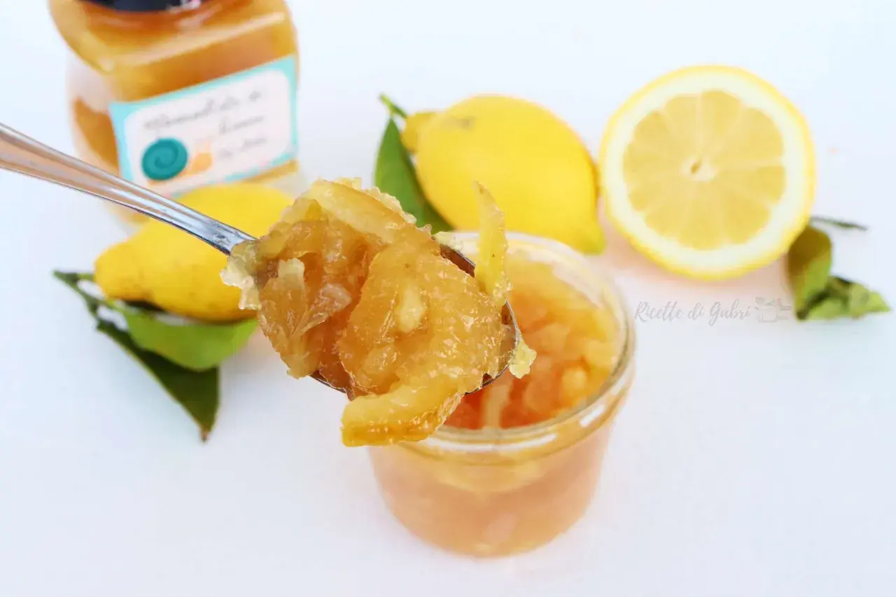 Marmellata di limone ricetta facile: un cucchiaio pieno di delizia, limoni freschi e un vasetto pronto da gustare.