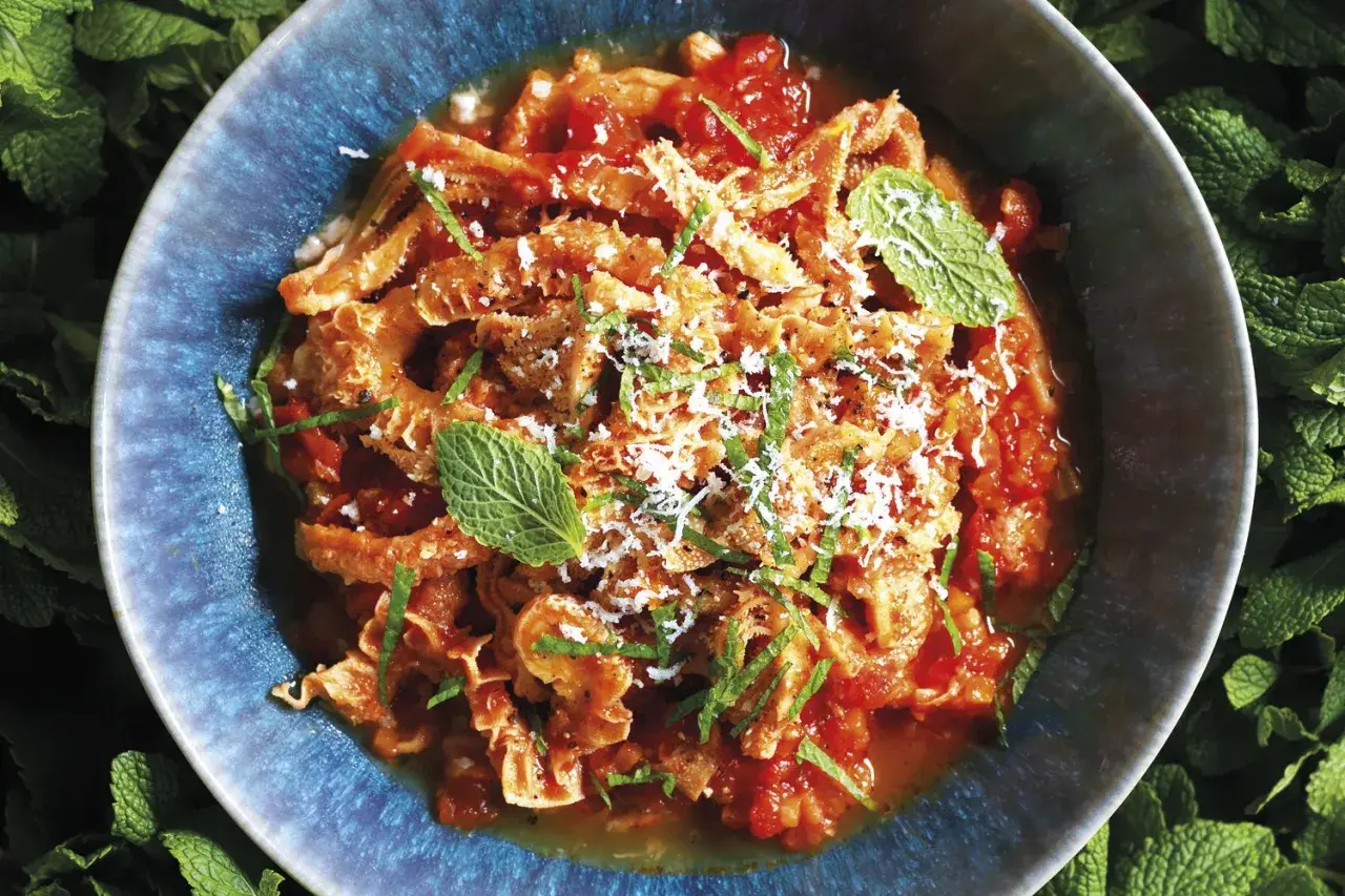 Trippa alla romana in un piatto blu, guarnita con menta e parmigiano. Un classico della cucina romana.